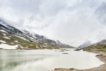 White lake and snowcapped mountains under cloudy sky — Stock Photo