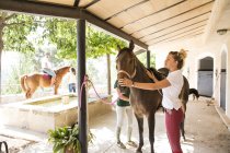 Pflegerinnen mit Pferd in ländlichen Ställen — Stockfoto