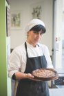 Retrato de panadero llevando pastel en la cafetería - foto de stock