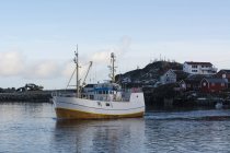 Barco de pesca que sale del puerto, Hamnoy, Islas Lofoten, Noruega - foto de stock