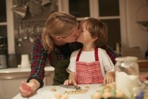 Женщина целует сына во время выпечки на кухне — стоковое фото