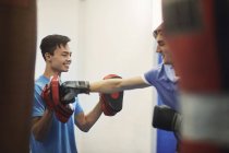 Male boxer training, punching teammate's punch mitt — Stock Photo