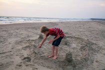 Junge bastelt Sandburg am Strand — Stockfoto