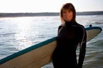 Femme debout avec une planche de surf — Photo de stock
