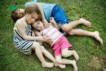 Crianças deitadas na grama juntas — Fotografia de Stock