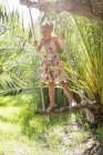 Дівчина стоїть гойдається на дереві гойдалки в саду — стокове фото