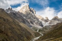Valle e montagne rocciose sotto cielo nuvoloso blu — Foto stock