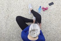 Reife Frau im Freien, Handgewichte, Wasser und Smartphone neben sich, erhabene Aussicht — Stockfoto