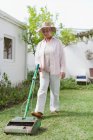 Older woman mowing lawn in backyard — Stock Photo