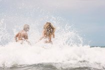 Парень и девушка прыгают в волну — стоковое фото