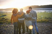 Вид ззаду чотирьох дорослих друзів, які спостерігають за заходом сонця над морем — стокове фото