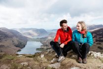 Молодая пара, сидящая на вершине холма, Honister Slate Mine, Buttermere, Crummock Water, Keswick, Lake District, Камбрия, Великобритания — стоковое фото