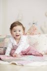 Portrait of baby girl, sitting on blanket, laughing — Stock Photo