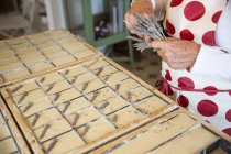 Средняя часть женщины наносит сушеную лаванду на мыло в мыльной мастерской ручной работы — стоковое фото