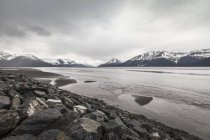 Snowcapped mountains and lake under cloudy sky — Stock Photo