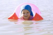 Portrait of female toddler wearing rubber ring and inflatable armbands in Lake Seeoner See, Bavaria, Germany — Stock Photo