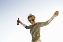 Retrato de mujer adulta mediana con los brazos abiertos contra el cielo azul soleado - foto de stock