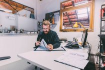 Trabajador metalúrgico masculino revisando diseños en oficina de forja - foto de stock