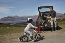 Padres viendo a su hijo montar en bicicleta, Loch Eishort, Isla de Skye, Hébridas, Escocia - foto de stock