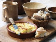 Сыр в терракотовой тарелке с ножом и хлебом — стоковое фото
