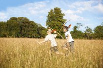 Dos niños pequeños corriendo con arcos y flechas - foto de stock