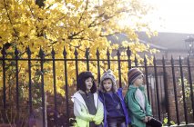 Three boys, outdoors, leaning against fence, in autumn — Stock Photo