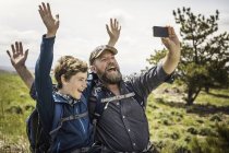 Father and teenage son waving for smartphone selfie on hiking trip, Cody, Wyoming, USA — Stock Photo