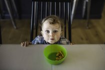 Portrait of blue eyed male toddler looking up from table — Stock Photo
