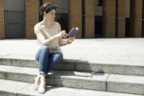 Frau sitzt auf Stufen und liest Notizbuch, Mailand, Italien — Stockfoto