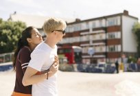 Donna abbracciare fidanzato in città skatepark — Foto stock