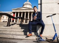 Бизнесмен рядом со скутером, Трафальгарская площадь, Лондон, Великобритания — стоковое фото