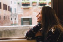 Femme regardant par la fenêtre, Venise, Italie — Photo de stock