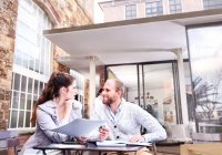 Mujer de negocios y hombre discutiendo el papeleo en el patio de oficinas - foto de stock