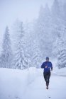 Maschio corridore che corre nella neve che cade, Gstaad, Svizzera — Foto stock