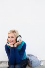 Femme souriante écoutant des écouteurs — Photo de stock
