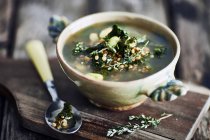 Bowl of broth on wooden cutting board — Stock Photo