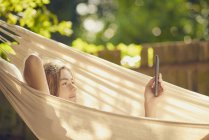 Teenager liegt in Gartenhängematte und surft mit digitalem Tablet — Stockfoto