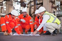 Workers with blueprints at oil refinery, selective focus — Stock Photo