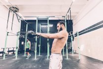 Young male cross trainer weightlifting kettlebell in gym — Stock Photo
