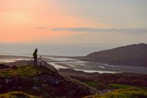 Велосипедист стоит на вершине холма — стоковое фото
