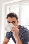 Чоловік п'є з чашки вдома — стокове фото