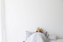 Mature woman in bed underneath quilt wearing golden crown — Stock Photo