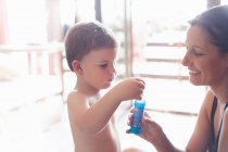 Madre e figlio soffiando bolle in casa — Foto stock