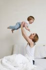 Portrait of mid adult woman holding up toddler girl — Stock Photo