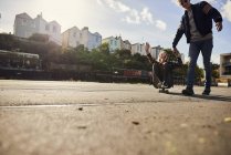 Zwei Freunde albern herum, junger Mann zieht junge Frau auf Skateboard, bristol, uk — Stockfoto