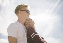 Жінка і хлопець проти сонячного світло-блакитного неба — стокове фото