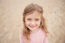Маленька дівчинка посміхається на пляжі проти піску — стокове фото