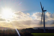 Céu iluminado pelo sol e turbina eólica na paisagem rural — Fotografia de Stock