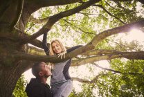 Личный тренер, поднимающий молодую женщину на дерево парка — стоковое фото