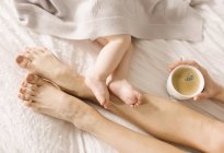Mother and baby bare feet on each other on bed — Stock Photo
